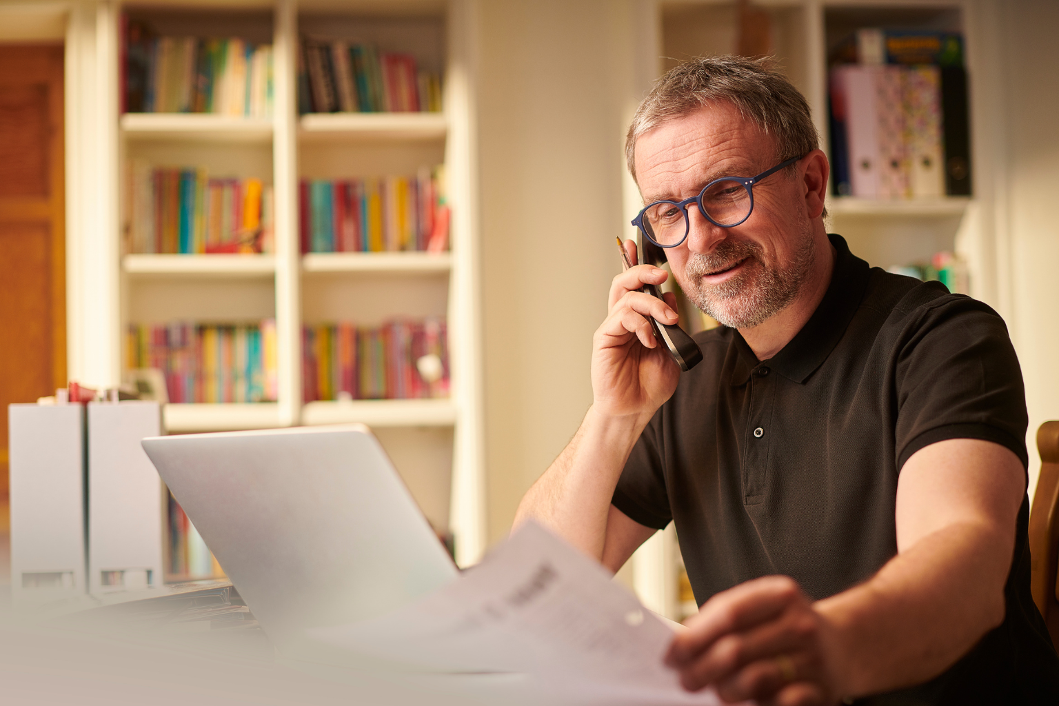 Small business owner on a phone call while reviewing documents at a desk representing a potential new customer reached through prospecting display ads